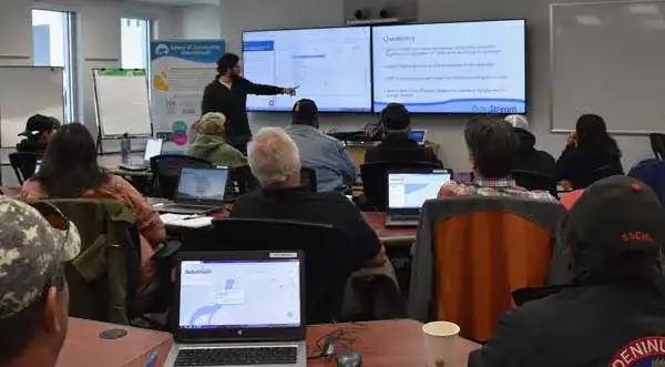 Data Specialist Patrick LeClair at the front of the room pointing to the screen as he does a Datathon in Yellowknife