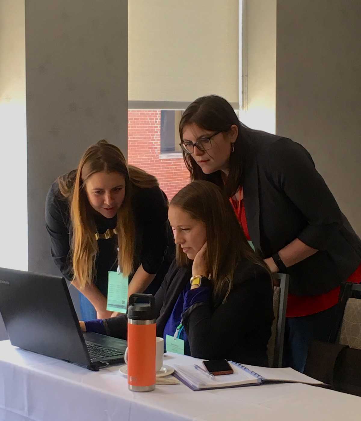 Chelsea Lobson, Emma Wattie, and Keila Miller looking at Atlantic DataStream on a laptop during a datathon