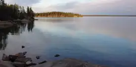 Un lac avec une île au loin et des rochers le long du rivage