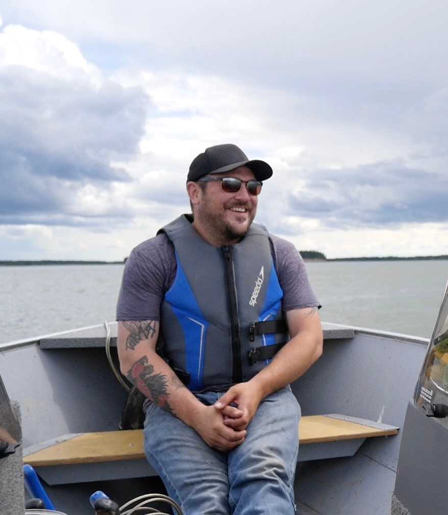 Mike Low wearing a lifejacket in a boat on the water