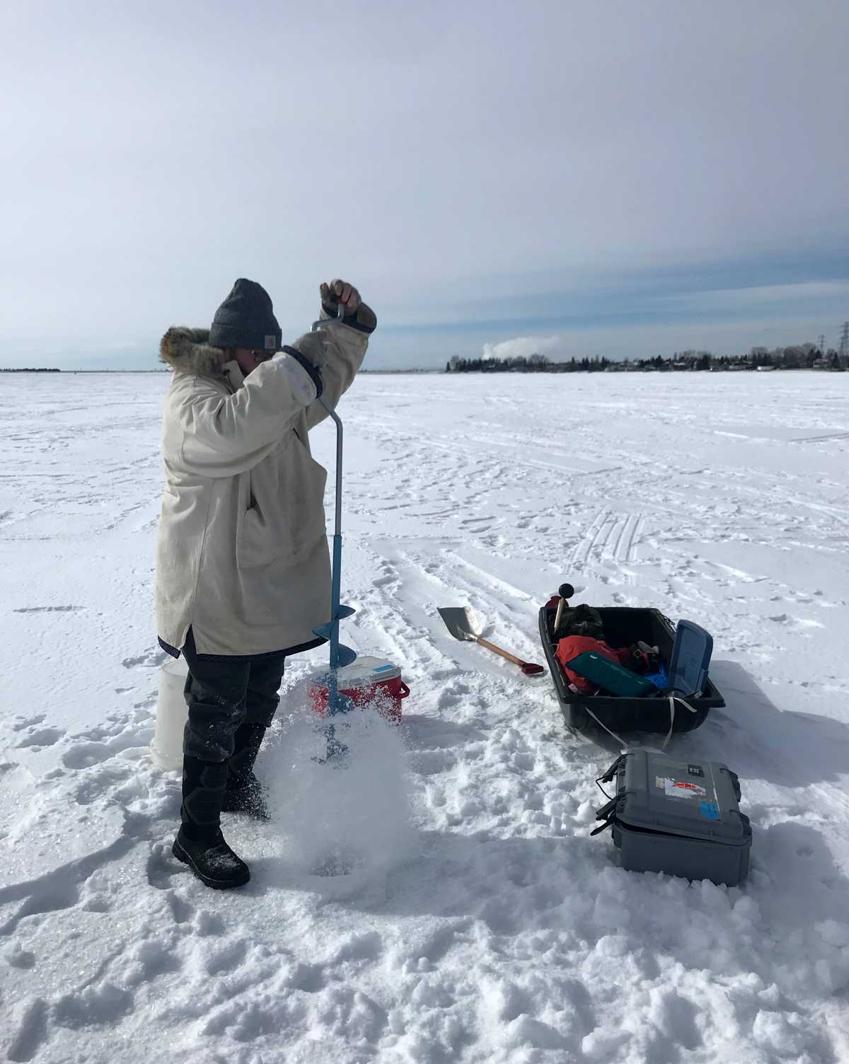 Rick Robinson, bénévole de LakeKeepers, utilise une tarière pour percer un trou dans le lac Chestermere.