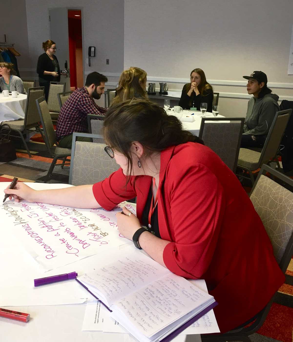 Emma Wattie writing notes at a mini roundtable