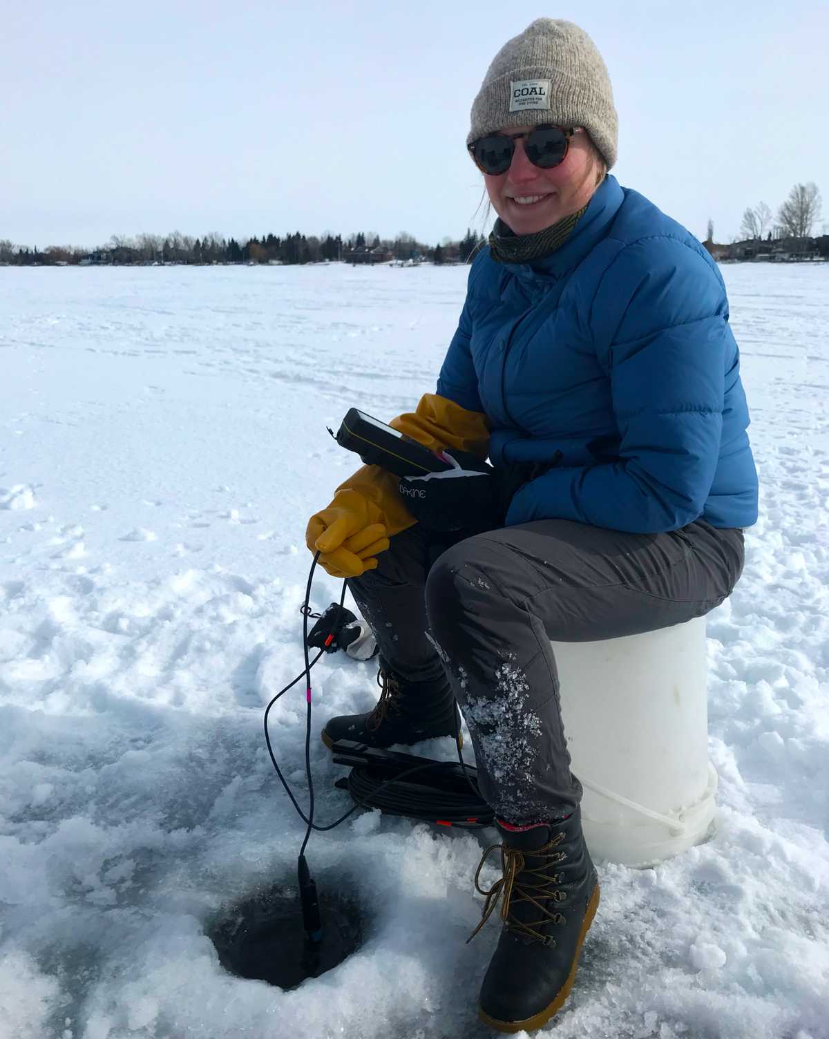 Mary Kruk, de DataStream, apprend comment les bénévoles d’hiver de LakeKeeper recueillent des données sur la qualité de l’eau, en utilisant une sonde pour mesurer la température et l’oxygène dissous, et en collectant des échantillons d’eau en bouteille pour les analyser en laboratoire.