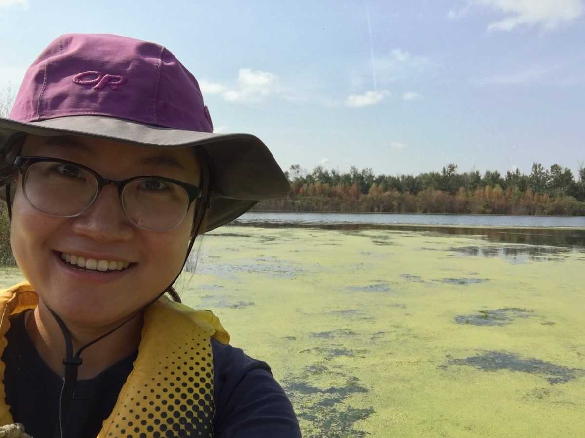 Selfie of a girl with algae covered lake in the background --- Selfie d'une fille avec un lac couvert d'algues en arrière-plan